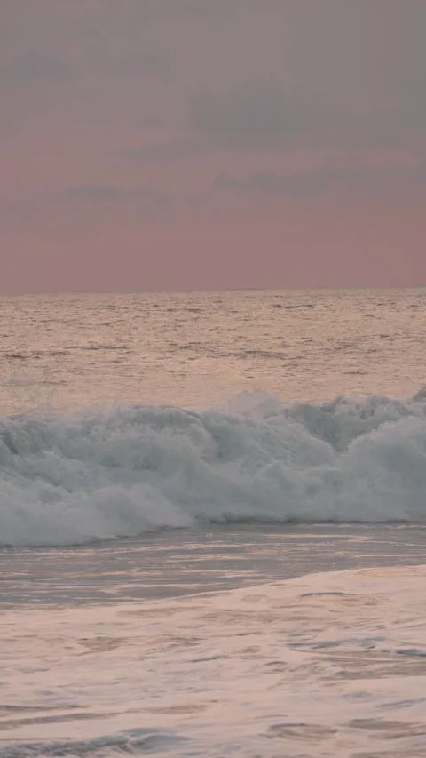 Gentle sea waves rolling onto a sandy beach under a beautiful pink sky at dusk 스톡 동영상 342737862