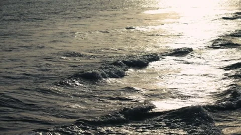 Gentle sea waves rolling onto the shore in warm sunlight. Calm sea surface with Stock Footage 334944067