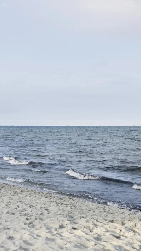 Gentle Sea Waves on Sandy Beach Under Cloudy Sky Stock Footage 340164272