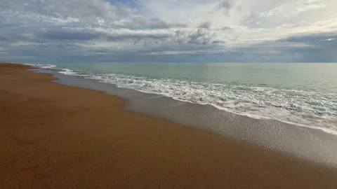 Gentle sea waves touching sandy beach under dramatic cloudy sky Stock Footage 324028843