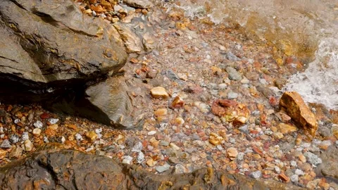 Gentle Sea Waves Washing Over Pebbles and Rocky Shoreline 動画素材 346737869