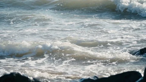 Gentle slow motion view of small waves lapping rocky beach Stock Footage 119534386