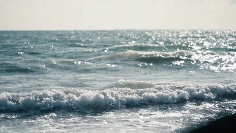 Gentle slow motion view of small turquoise waves lapping rocky beach Stock Footage 119534703
