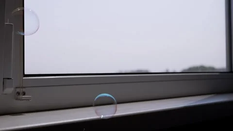 Gentle Soap Bubbles Floating by a Bright Window Stock Footage 317561377