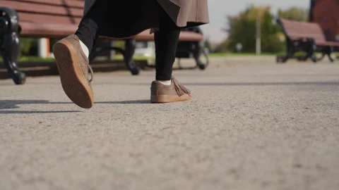 Gentle steps near park bench. Serene morning scene with suede shoes. Calm and Stock Footage 330526018