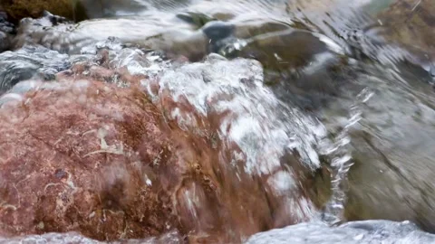 A gentle stream flows over smooth stones Stock Footage 313218813