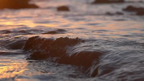 Gentle sunset water flows smoothly over dark wet coastal rocks. Stock Footage 337408866