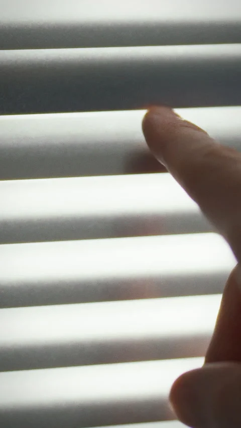 Gentle touch adjusts window blinds to create a calming light in the room Stock Footage 331591174