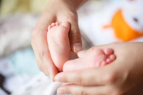 A gentle touch cradles tiny baby feet, symbolizing love and care in nurturing Stock Photos