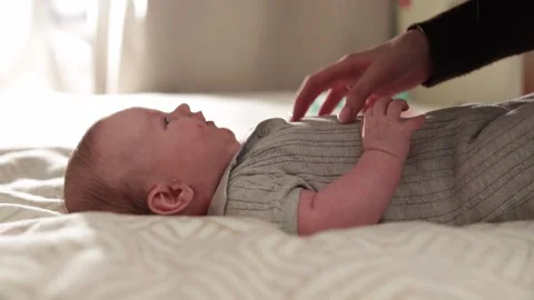Gentle touch of a parent's hand caressing a newborn baby's chest on a soft Stock Footage 340629874