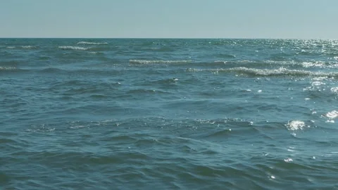 Gentle turquoise waves of the sea in the rays of the evening sun against a .. 库存影片 339090468