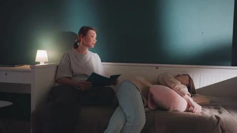 Gentle voice and warm light foster calming family moments. Evening reading time Stock Footage 336867673