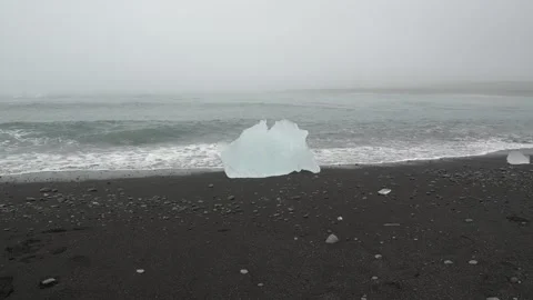 Gentle Waves Around a Glacial Ice Chunk on Diamond Beach in Iceland 库存影片 339953825