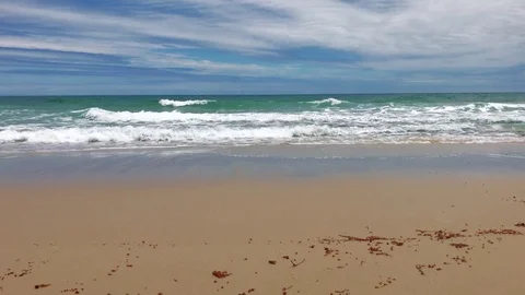 Gentle waves breaking on beach shoreline with boat in the horizon shot in 4K Video stock 71315567