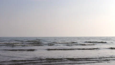 Gentle waves brushing up against the sandy beach at sunset Stock Footage 233990713