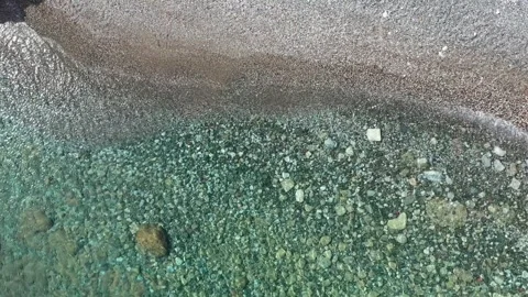 Gentle waves caressing a pebble beach under a bright sunny sky Vídeo Stock 305512735