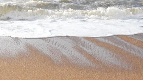Gentle waves cascading over sun-drenched beach, forming rhythmic patterns Video stock 308706503