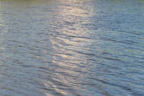 Gentle waves dance under a soft sunset glow painting the tranquil surface o.. Stock Photos
