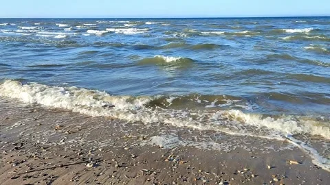 Gentle waves lap against the sandy shore Stock Footage 312253952