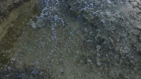 Gentle waves lap on rocks Stock Footage 163313972