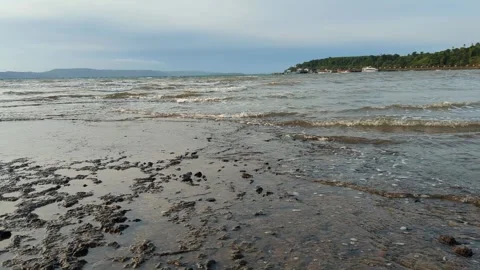 Gentle waves lap the sandy shore on a deserted beach at sunrise Stock Footage 276602348