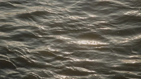 Gentle waves lap in the sea, river or lake at dusk or sunset with sun reflecting 스톡 동영상 129277704