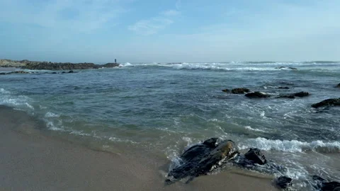 Gentle waves lapping on beach and man fishing in distance 動画素材 194198799