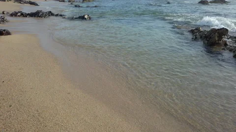 Gentle waves lapping on a sandy beach with rocks on shore, close up 動画素材 194201993
