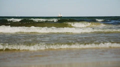 Gentle waves lapping the shore with sailboat in the distance Stock Footage 312207404