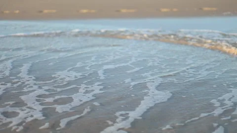 Gentle waves lapping on the shore at sunrise, capturing the serene beauty of Stock Footage 287787092