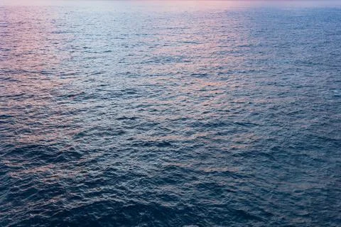 Gentle waves ocean surface reflecting the soft hues of twilight dusk tranquil Stock Photos