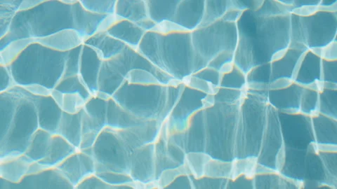 Gentle waves ripple in the pool as sunlight filters through, casting mesmerizing Stock Footage 296718509
