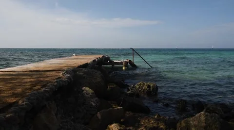 Gentle waves roll past old dock and rocks. Stock Footage 43379918