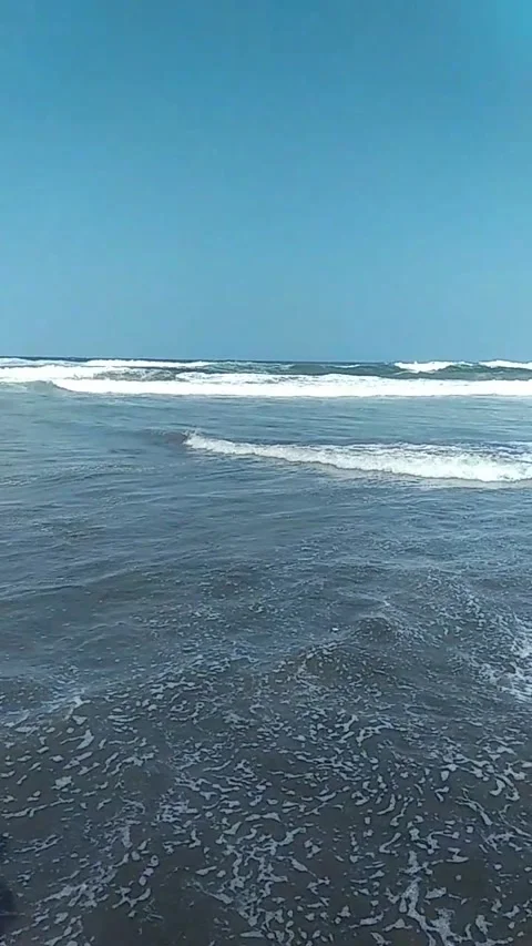 Gentle Waves Rolling on a Beach with a Clear Blue Sky Background Stock Footage 280727871