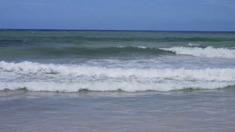 Gentle waves rolling on sandy beach under blue sky Video stock 302156462