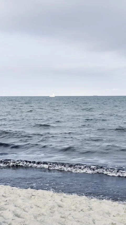Gentle Waves Rolling onto Sandy Beach Under Soft Cloudy Sky Stock Footage 340163846