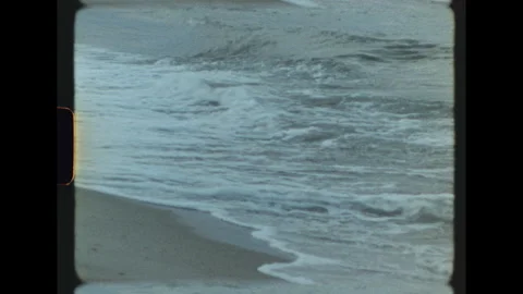 Gentle waves rolling onto the shore on vintage super 8 film Stock Footage 346180547
