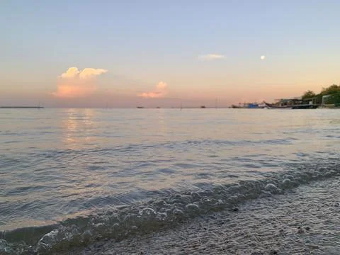 Gentle Waves on Sandy Shore at Sunset with Moon in Tanjung Lesung Beach Stock Photos