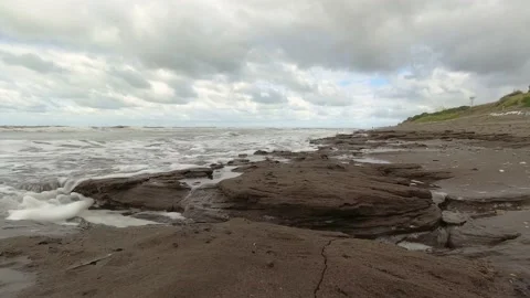 Gentle waves on the shore of a beach lapping the rocks Stock Footage 171355111