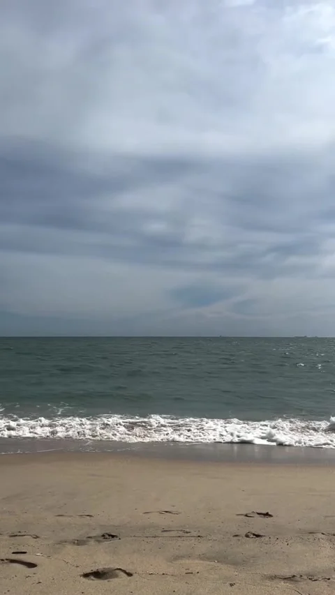 Gentle Waves Splashing on a Sandy Beach Under Cloudy Skies Video stock 342264684