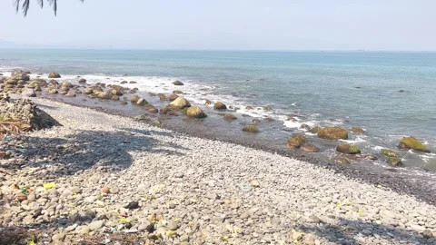 Gentle waves washing over a pebble beach on a sunny day Stock Footage 342044776