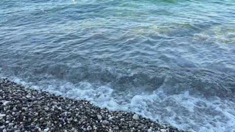Gentle Waves Washing Over Pebbles Along Clear Blue Green Shoreline, Tranquil 動画素材 346757097