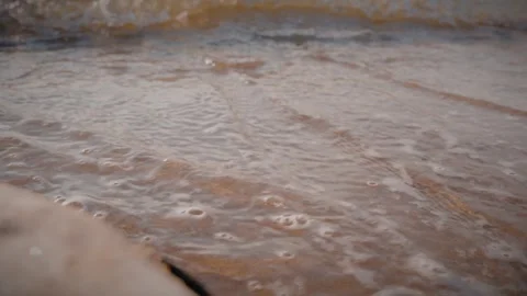 Gentle waves washing over sandy beach shore at sunset creating bubbles Stock Footage 292868831