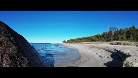 Gentle waves washing onto a sandy beach on a sunny day, static shot Stock Footage 337555856