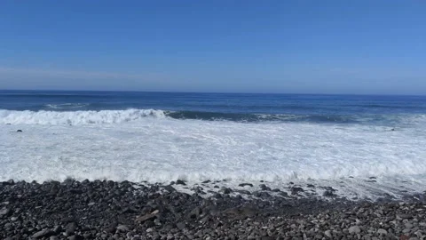 Gentle waves with white foam breaking on a volcanic stone beach Stock Footage 201935863