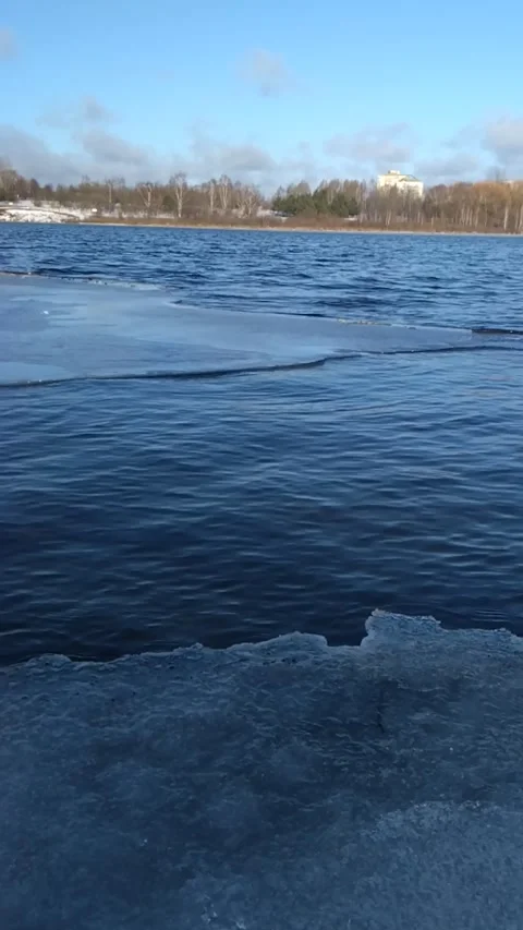Gentle Winter Waves Lapping Against Melting Ice Shoreline Stock Footage 306070685