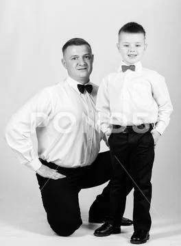 Gentleman upbringing. Formal event. Little son following fathers example of Stock Photos