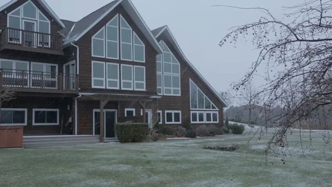 Gently falling snow in front of chalet style house panning Stock Footage 77280890
