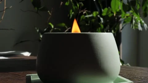 A gently glowing flame burns in a pale gypsum candle holder on wooden surface Stock Footage 310337664