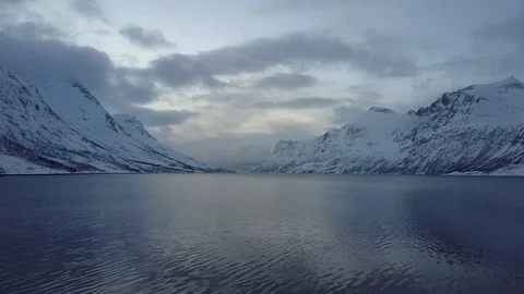 Gently hovering over a scandinavic lake with snowy mountains surrounding. Stock Footage 82798761